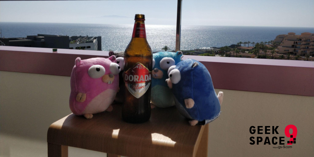 4 gopher plushes standing around a big Dorada beer bootle in front of a balcony railing, in the background there is a wide view over the ocean